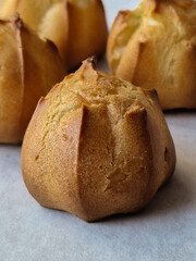 pate a choux pastry profiteroles on baking paper, pastry background, copy space, vertical