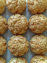 Choux au Craquelin, crispy Cream Puffs, pate a choux pastry profiteroles with craqueline on baking paper, pastry background, copy space, vertical