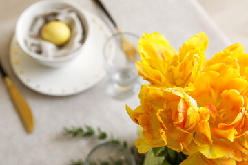Bouquet of beautiful yellow tulips on table served for Easter celebration, closeup
