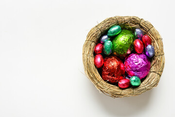 Nest with chocolate Easter eggs on white background