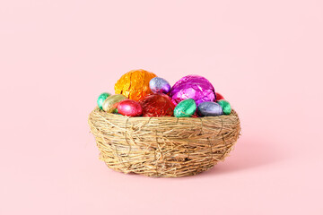 Fototapeta na wymiar Nest with different chocolate Easter eggs on pink background