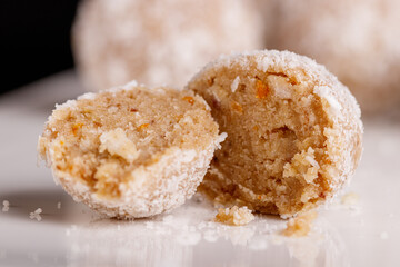 Beautiful sweets with coconut on a white plate on a black background