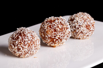 Beautiful sweets with coconut on a white plate on a black background