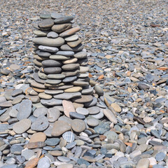 a pyramid of sea pebbles of different sizes on a sunny stone beach