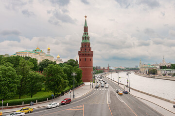 Embankment of the Moscow River with many cars. The towers of the Moscow Kremlin against the background of a cloudy spring sky