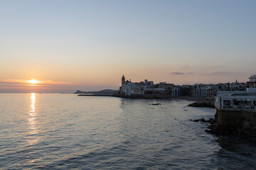 Picturesque sea evening landscape. Sunset over the mediterranean sea. Evening city, sea and sunset. The sun is above the horizon line.