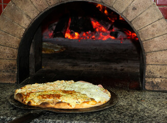 Pizza pronta, na boca do forno a lenha