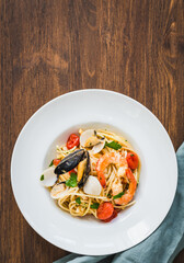 Pasta spaghetti with seafood sauce plate on wooden table top view copy space background.