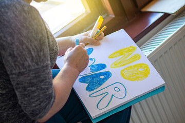 A woman draws a poster of no war before the rally. Russia's war with Ukraine
