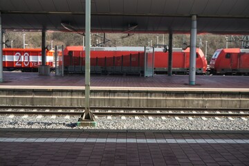 Bahnhof Panorama mit Gleisen, schienen, Überdachungen und rotem Zug bei Sonne im Winter