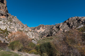 Fototapeta na wymiar Blue sky over the vertical walls of the mountains on the route of the Monachil river, in Los Cahorros, Granada, Spain.