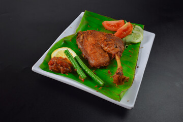 Juicy grilled chicken halves with mouth-watering golden brown skin served on a white plate on a dark background.