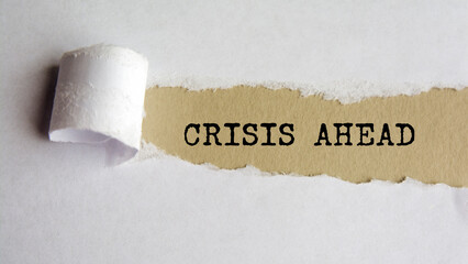 crisis ahead. words. text on grey paper on torn paper background