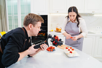 A videographer takes a video for a cooks or pastry chef in kitchen.