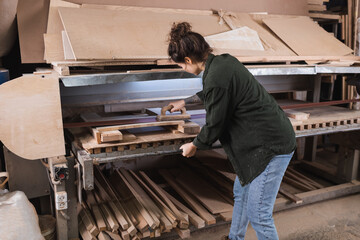 Carpenter polishing plank near boards in workshop.