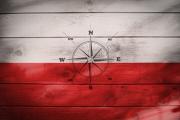 Flaga polski namalowana na drewnianych deskach z różą wiatrów.