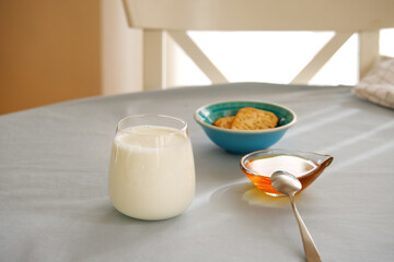 Glass of milk, honey and whole wheat cookies on the table.