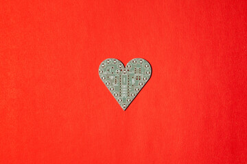 Circuit board in the shape of heart on red background.