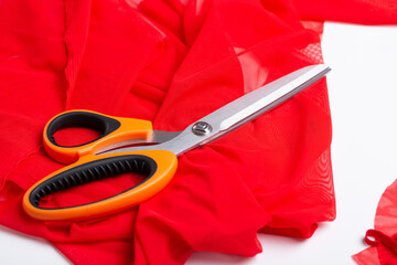Sewing accessories on a white table. Scissors, measuring tape, fabric, cloth, red tape.