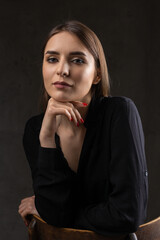 Portrait of a young brunette with long hair in the studio. Dramatic photo in dark colors.