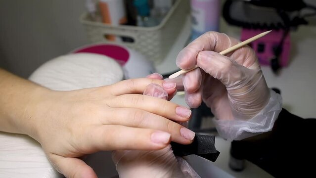 the manicure and pedicure master cleans the nail with a wooden stick