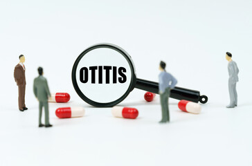 On a white surface are pills, figurines of people and a magnifying glass with the inscription - Otitis