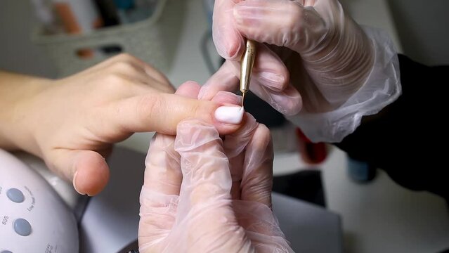 manicure and pedicure master apply nail polish to the nail with a thin brush