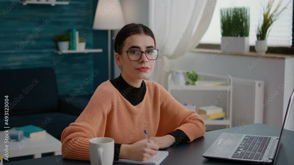 Poster portrait of young student taking notes on textbook in online class on laptop, attending remote cours