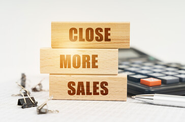On the reports is a pen, calculator, clips and wooden boards with the inscription - Close More Sales