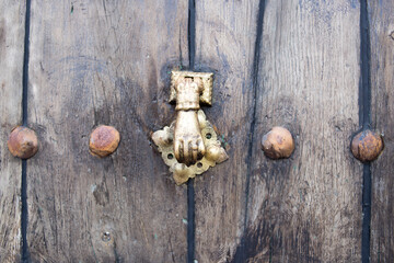 Knocker on old wooden door with golden nails