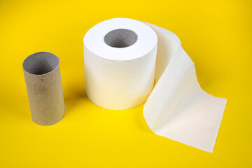 one whole and one finished toilet paper roll on a yellow background	