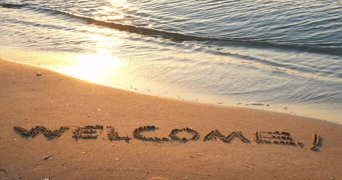 Welcome sign on the shore. A view of the word welcome on the wet sand on the beach.