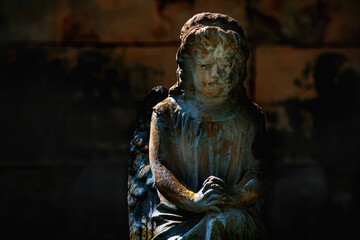 Praying angel. Fragment of a very ancient statue. Copy space.