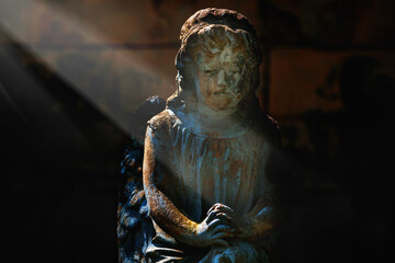 Praying angel in rays of light. Fragment of a very ancient statue.