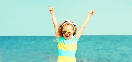 Summer portrait of happy little girl child having fun on beach over sea background, blank copy...
