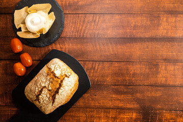 Freshly baked whole wheat bread with with curd cheese and cherry tomatoes. Dark  wooden table background