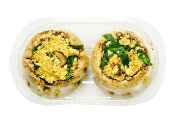 Two uncooked stuffed mushrooms in a plastic tray on white isolated background. Food industry product