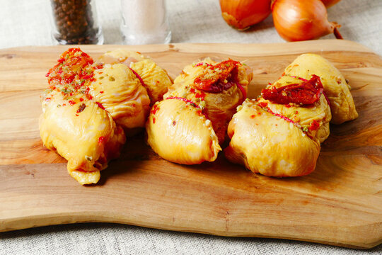 Rolled corn fed chicken thigs with herbs on a wooden board. Poultry product.
