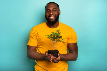 Man holds and takes care of a small tree