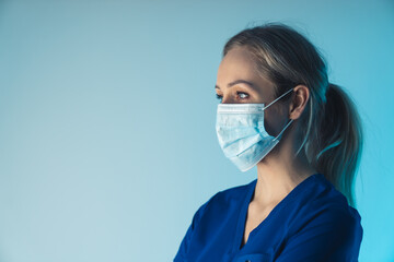 European woman nurse in her 30s observing surgery while wearing facial mask that covers her mouth...