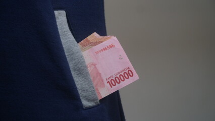 Indonesian rupiah banknote in jacket pocket, 100,000 rupiah