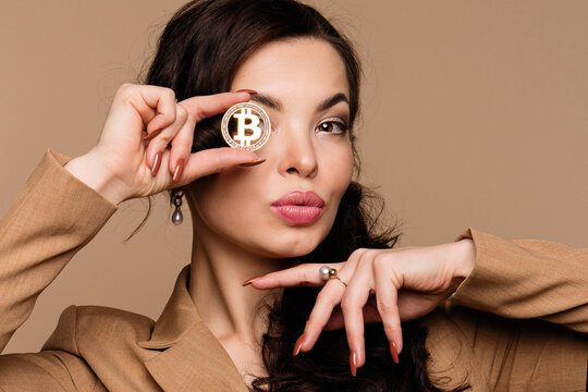 Cryptocurrency and blockchain. Girl shows btc coin holding in front of eye. Woman holding golden bitcoin and looking at camera. Advertise of digital money btc coin for e-commerce and nft projects - Powered by Adobe