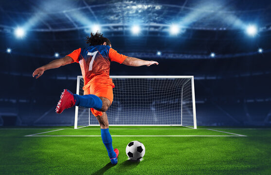 Soccer scene at night match with player in an orange and blue uniform kicking the penalty kick - Powered by Adobe