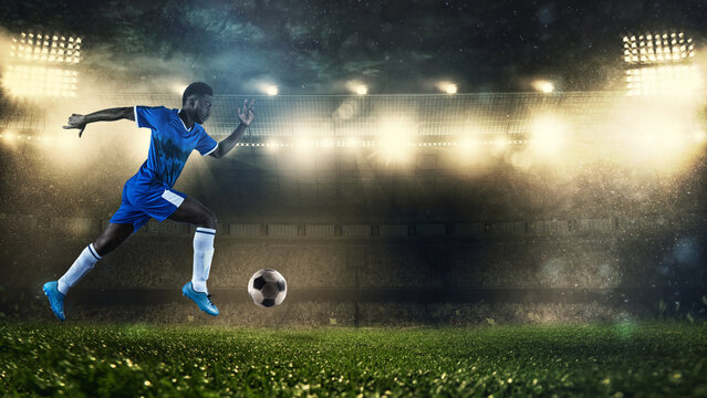 Soccer player in blue uniform sprinting fast with the ball at the stadium