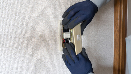 スイッチカバー・スイッチプレートを外す作業員　電気工事イメージ