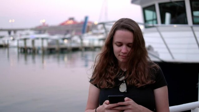 Young woman texting on her cellphone at the Port of Miami - travel photography