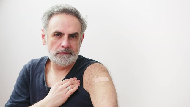 Immunization of the elderly people - caucasian man showing the vaccination arm patch influenza. High quality 4k footage