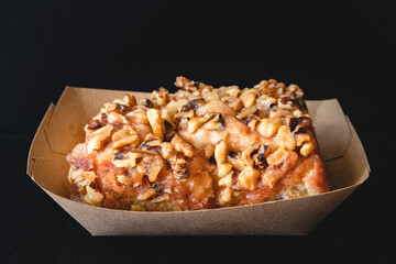 Fresh baked Walnut Frosted cinnamon roll close up on black background