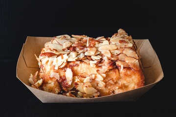 Fresh baked Almond Frosted cinnamon roll close up on black background