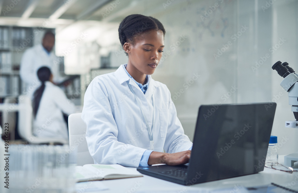 Poster the harder she works, the closer the cure. shot of a young scientist using a laptop while conducting